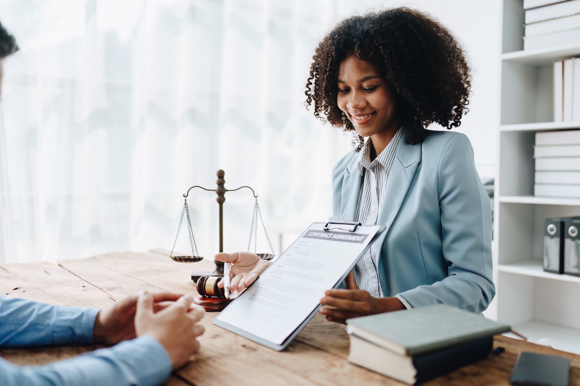 Young African American lawyer studying a case for a client and signing a legal contract to fight her opponent in court. Legal and lawyer concepts.